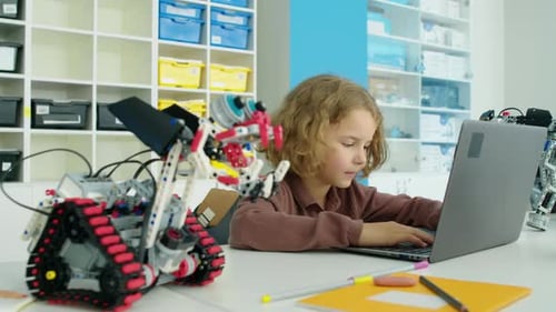 Preteen Caucasian Boy Writing Software on Laptop for Electric Robot