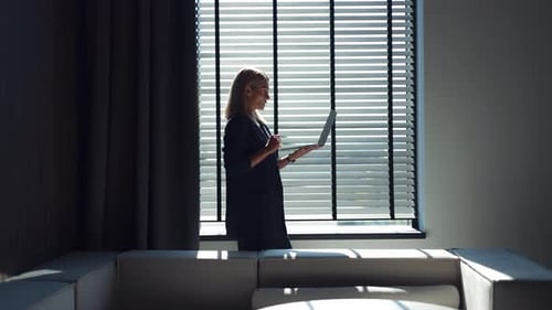Formally Dressed Woman Using Wireless Laptop for Video Call at Dark Office