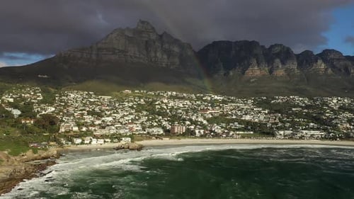 RAINBOW Aerial Tilt Shot of Cape Town's Camps Bay Beach with Table Mountain in the Background at Sun