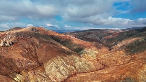 Aerial View of Arid Mountains and Farmland Under Dramatic Clouds