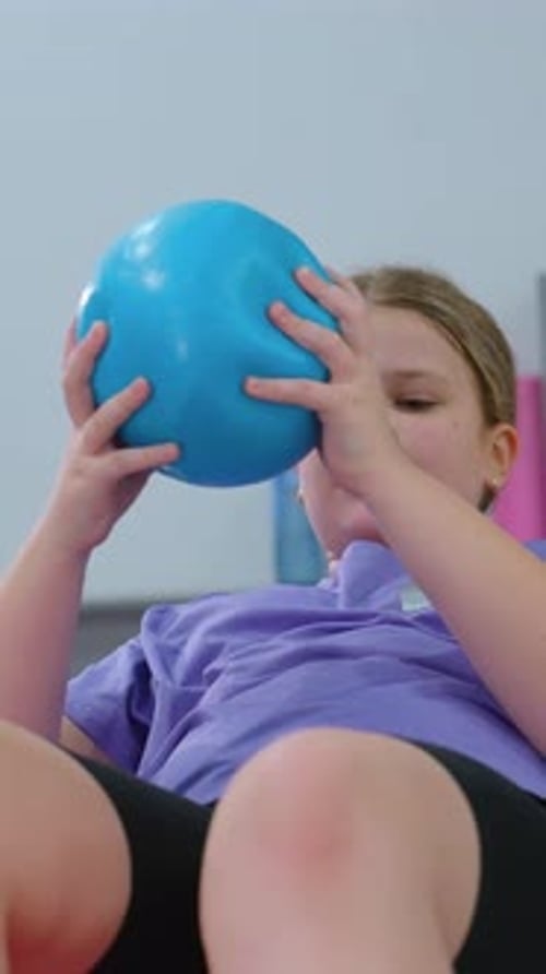 Girl Practicing Core Balance on Stability Ball During Gym Workout Session