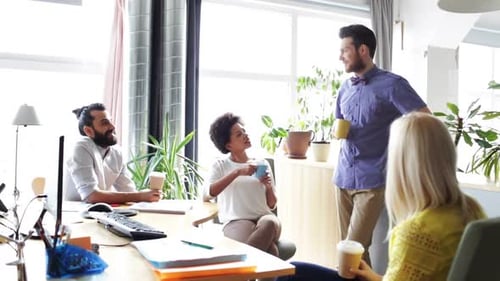 Happy multiethnic team of young professionals drinking coffee in the office
