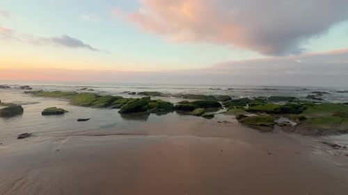 Walking along an idyllic beach with low water exposed rocks on a calm afternoon