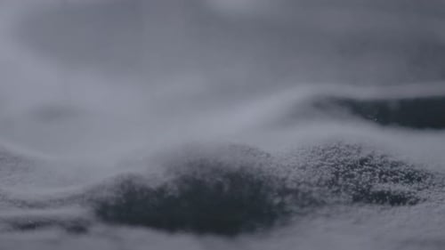 Fine sugar particles cascading in slow motion, forming delicate dunes and patterns up close