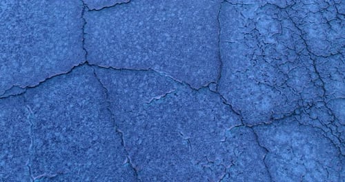 Footage above the cracked salty desert colored blue at sunset.