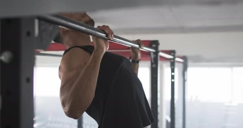 Exercising on pull-up bar, man doing pull-ups in gym