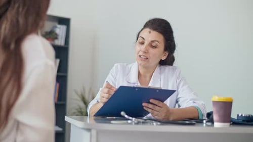 A Woman is Visiting a Doctor at Clinic Female Doctor Examining and Consulting Young Woman in the