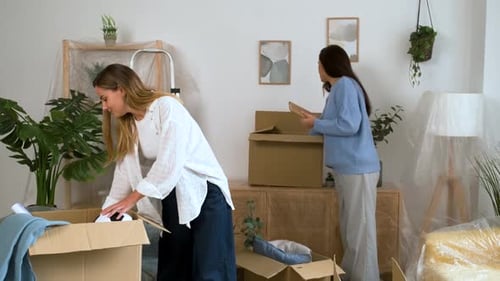 Young Women Unpacking Moving Boxes in Bright Apartment
