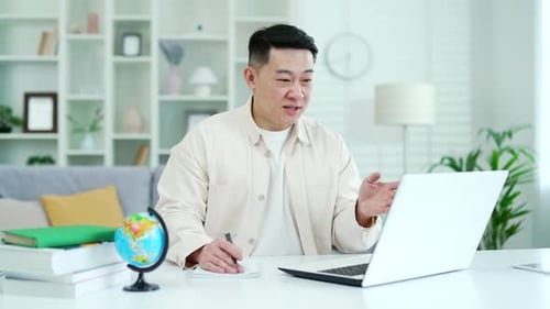 Man At Desk Engaged in Video Call on Laptop