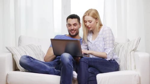 Couple Relaxing on Sofa with Laptop Computer