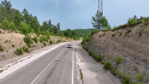 Aerial View of Cars Driving on a Winding Highway Through Steep Rocky Mountainous Terrain with Sparse