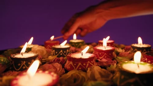 Hand Lighting Diyas with Flowers for Diwali Festival