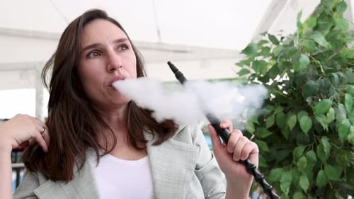 girl woman smoking hookah in terrace restaurant sitting with coffee cup on table,typing message