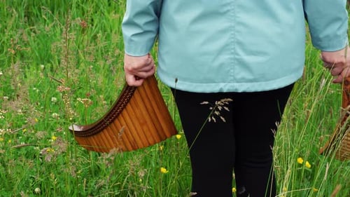 Una mujer joven balancea dos flautas de pan en la naturaleza