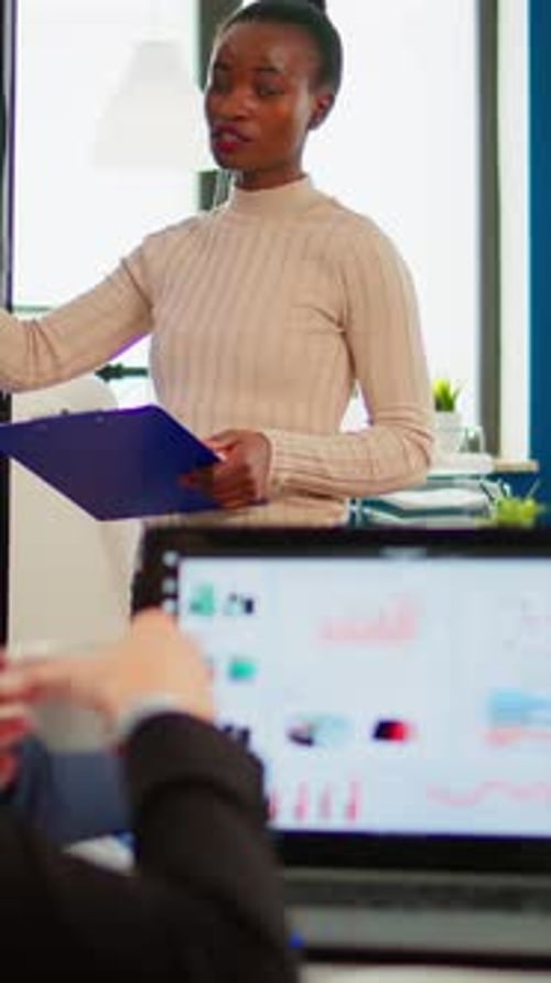 Professional Woman Presenting Data to Coworkers in Office
