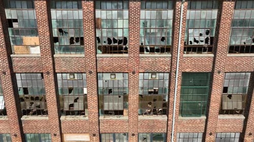 Old, abandoned brick building with shattered glass windows. Aerial close up.