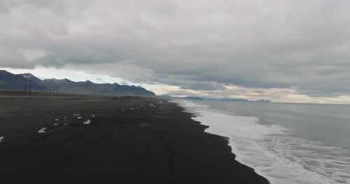 aerial movement over coastline of black beach at diamond beach, Jökulsárlón Glacier Lagoon, iceland
