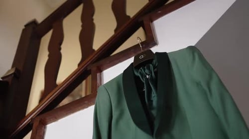 Green groom's wedding suit hanging by staircase