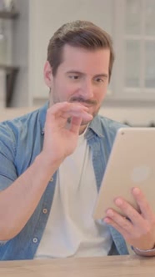 Man Cheers Using Tablet at Table Indoors