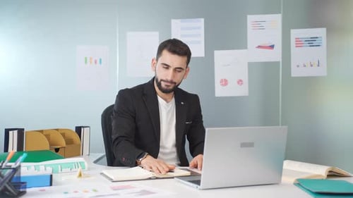 Young Adult at Desk Folds Paper Airplane