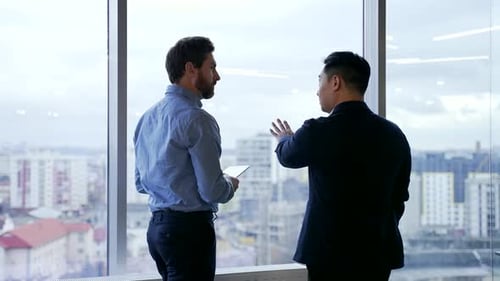 silhouette of employees talking in front of the window in modern office. Business people two partner