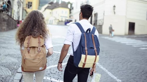 Couple with backpacks walking through cobblestone street