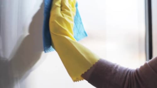 Woman cleaning window with spray and cleaning rag