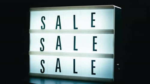 Illuminated Sale Sign Against Black Background for Advertising