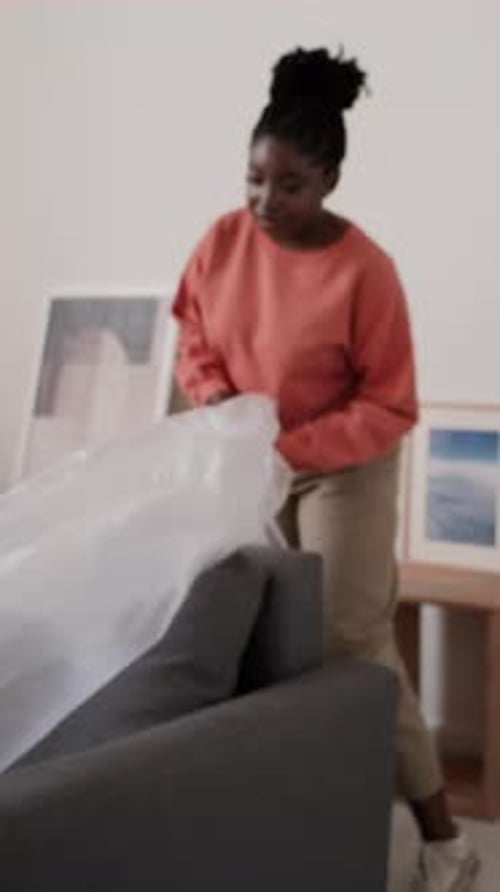 Couple Removing Plastic Cover from Sofa in New House