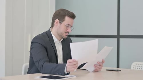 Businessman Reading Documents in Office, Paperwork