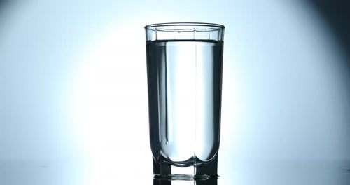 Ice cubes falling into clear glass with water