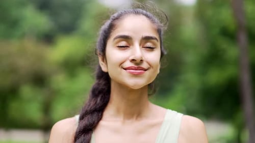 Close up portrait young happy woman standing in nature between forest trees relaxes, breathes fresh