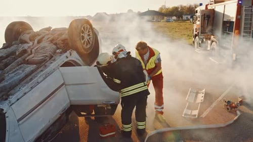 On the Car Crash Traffic Accident Scene: Rescue Team of Firefighters Pull Female Victim out of Roll