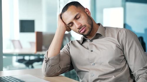 Sleepy employee man in office bored, lazy and tired while working on proposal or email. Pensive male