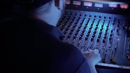 A man is using a mixing desk in a sound audio recording studio.