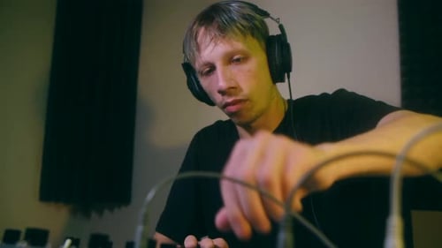 Man Adjusting Knobs on Music Mixing Board