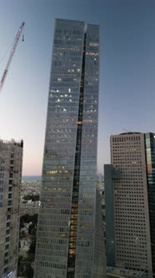 Aerial shot of cityscape by sea against sky at sunset, drone descending forward over city - Tel Aviv