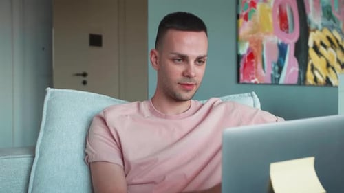 Young Adult Using Laptop on Couch Indoors