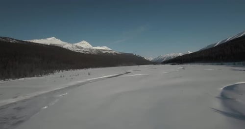 fpv drone shot over frozen river in canadian rocky mountains during winter