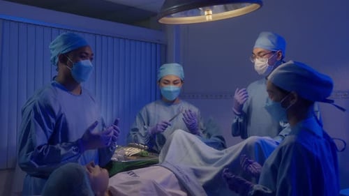 Assisting Nurse Handing Surgical Tool To Professional Surgeon In The Operating Room. medium shot