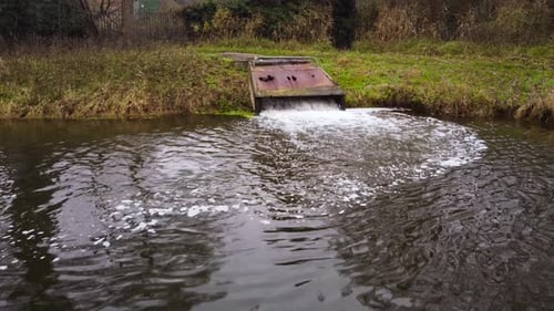 Water pollution, factory sewage water falling on lake from rusty concrete tube - drone dolly shot