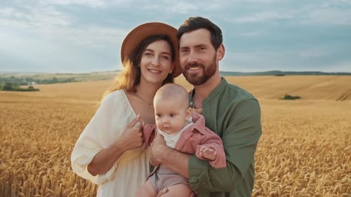 Portrait of Happy Caucasian Family with Little Baby Girl Standing on Wheat Field Smiling to the