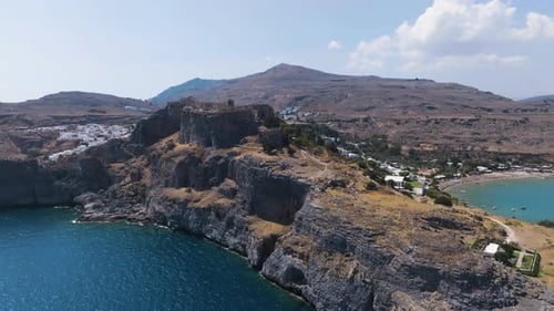 Drone survolant la côte rocheuse de la forteresse de Lindos au sommet d'une colline sous le soleil de Rhodes