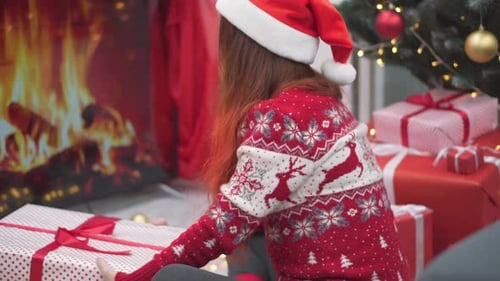 Woman Wrapping Christmas Presents by the Fireplace