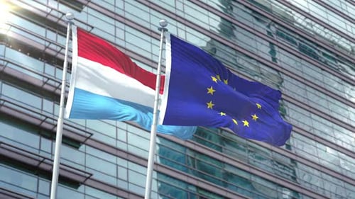 Luxembourg and European Union Flags Waving with Modern Glass Building