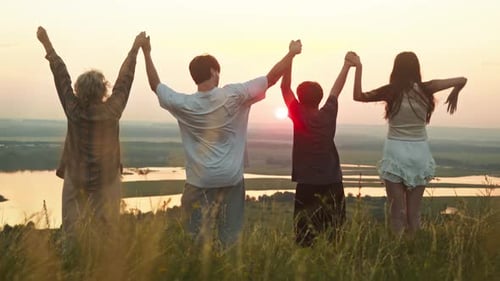 Happy Family Fooling Around in Nature on the Background of Sunrise Holding Hands Tightly Standing in