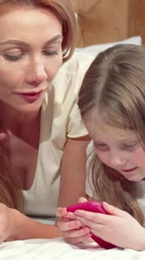 Woman and girl looking at a phone in bed