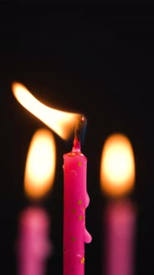 Three Cake Candles Burning on a Black Background