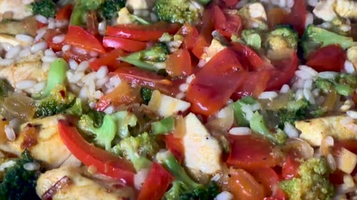 Boiling water in a pan with rice, tomato, chicken, broccoli, pepper and spices. Cooking italian riso