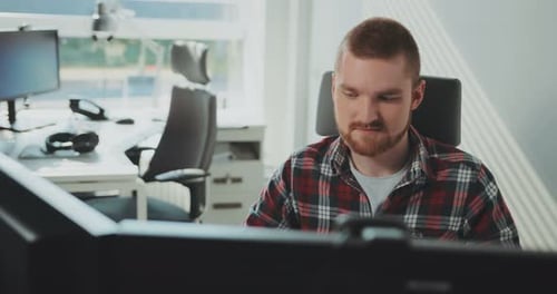 Un jeune homme barbu est assis devant un ordinateur travaille au bureau Design contemporain Designer Computer